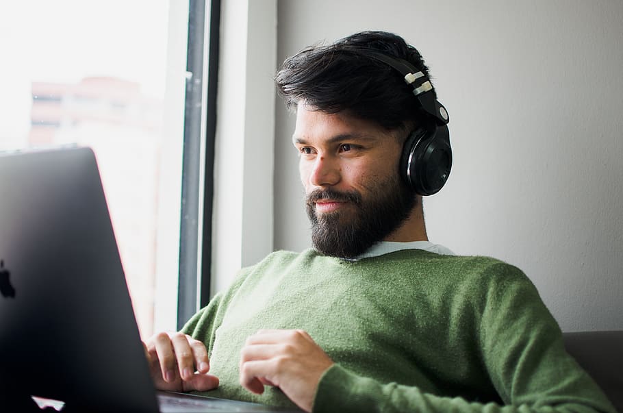 man-wearing-headphones-while-looking-at-macbook